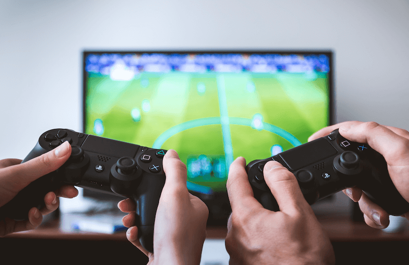 two-hands-holding-video-game-controllers-with-video-game-on-screnn
