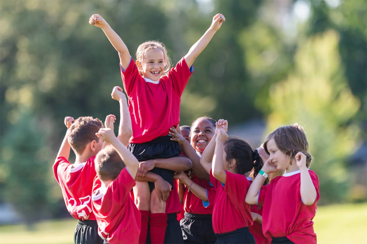 young-soccer-players-lifting-girl-up-in-huddle