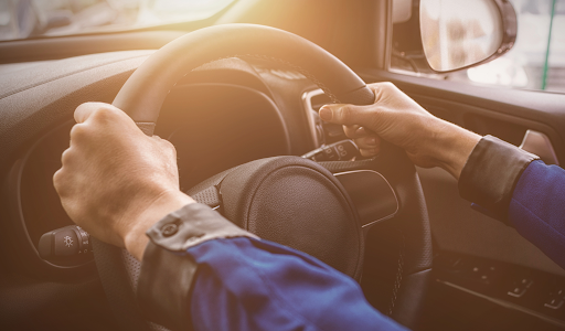 two-hands-on-driving-wheel-with-sunlight-shining-in